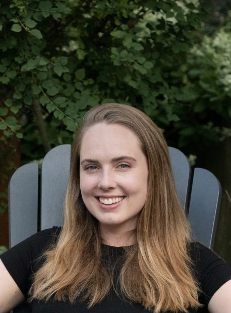 Grace Melcher sitting in Adirondack chair with trees in the background